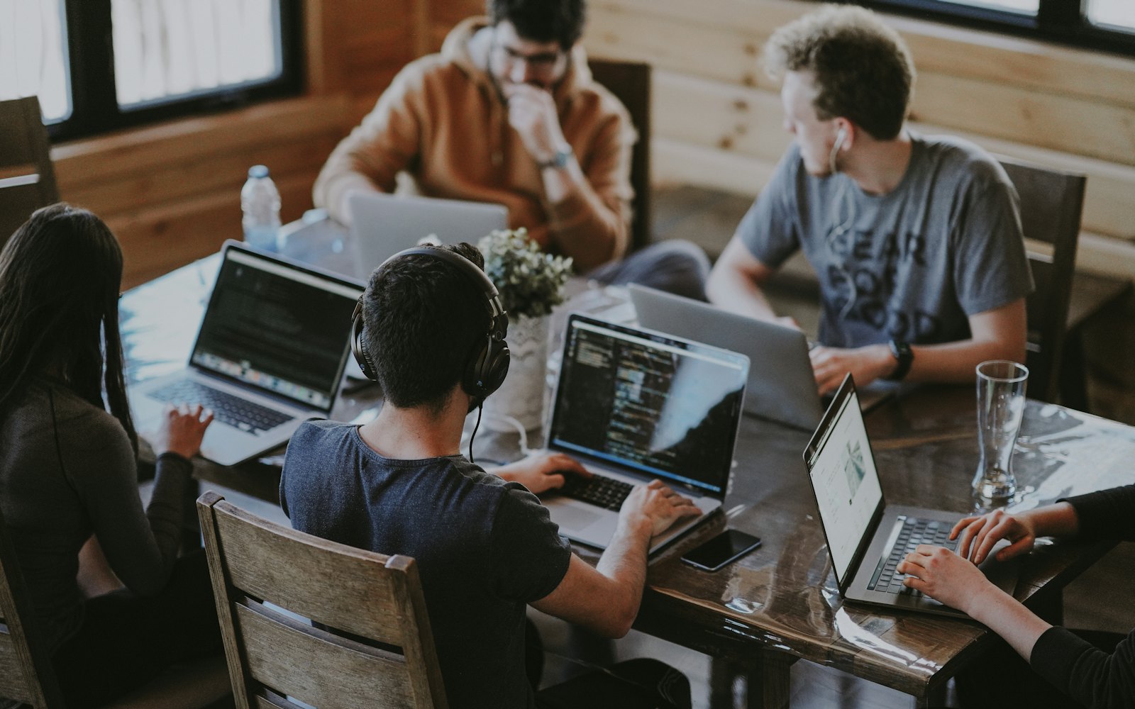 A team gathered around a table working together on laptops.