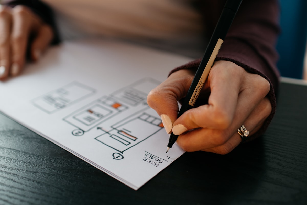A hand sketching interface wireframes on paper.